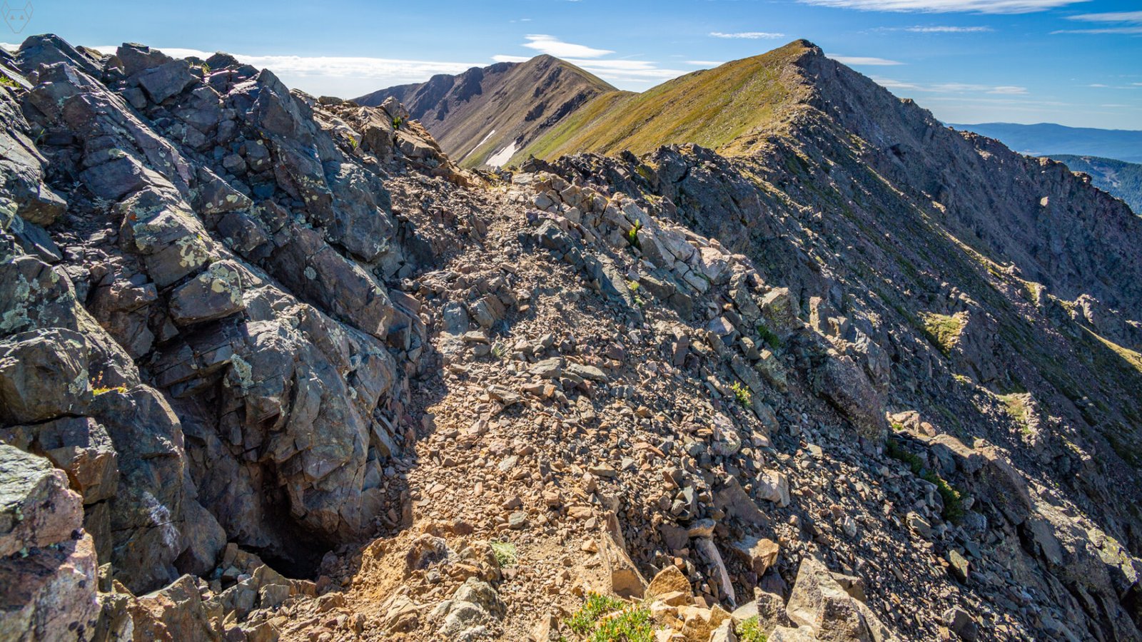 Jagged boulders gradually erode as the trail traverses a narrow alpine ridge.